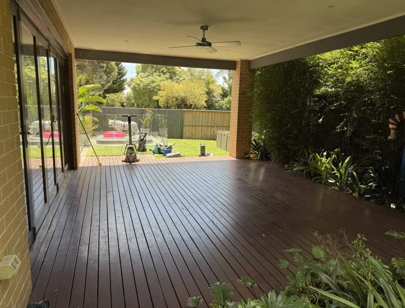 Deck carpentry project with tools and materials on a backyard patio.