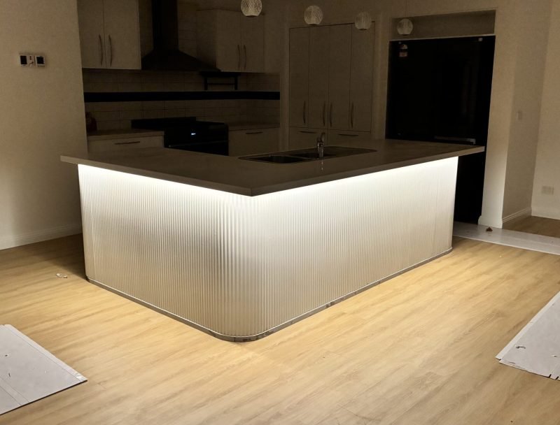 Modern kitchen island with fluted panel carpentry and LED lighting