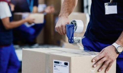 closeup-delivery-man-closing-carboard-box-with-tape-while-preparing-packages-shipment_637285-2244